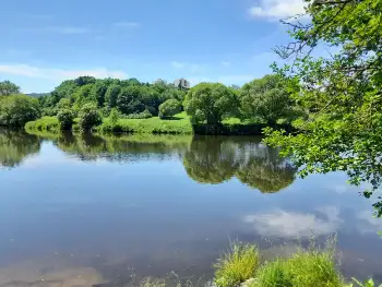 Weiter Blick über den Fluss mit offenen Wiesenufern
