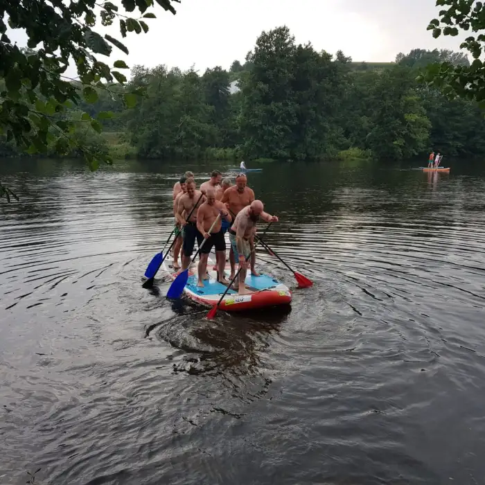 Gruppe steht gemeinsam auf einem gro&szlig;en Stand-up-Paddling-Board